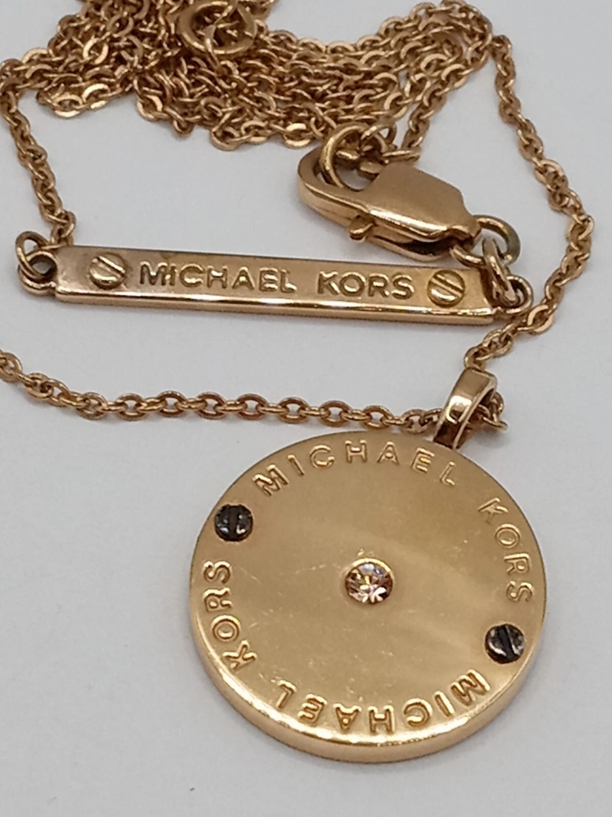 Collana Michael Kors logo disco ciondolo eredità tono oro cristallo pietra centrale