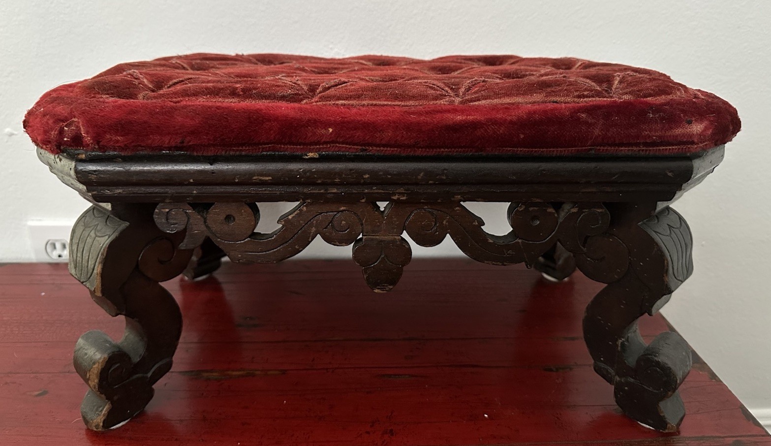 Red tufted velvet Victorian footstool with carved wood legs.