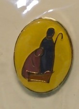 Prendedor religioso vintage con arte de belén sobre fondo amarillo