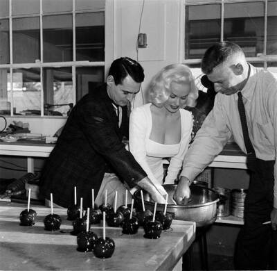 Actress Mamie Van Doren makes caramel apples with Ray Anthony duri- 1957 Photo