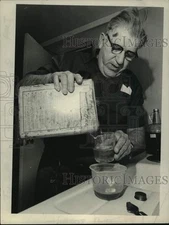 1974 Press Photo George Bell pours chemical from a can into a jar in New York