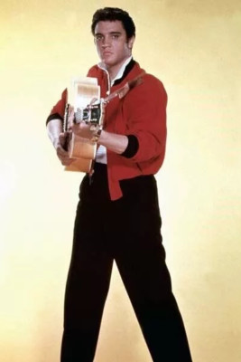 Elvis Presley posiert in roter Jacke mit seiner Gitarre