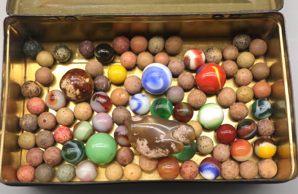 A rare lot of antique handmade glass and clay marbles in a vintage tin — tiny, tactile history that doubles as a stunning display piece.
