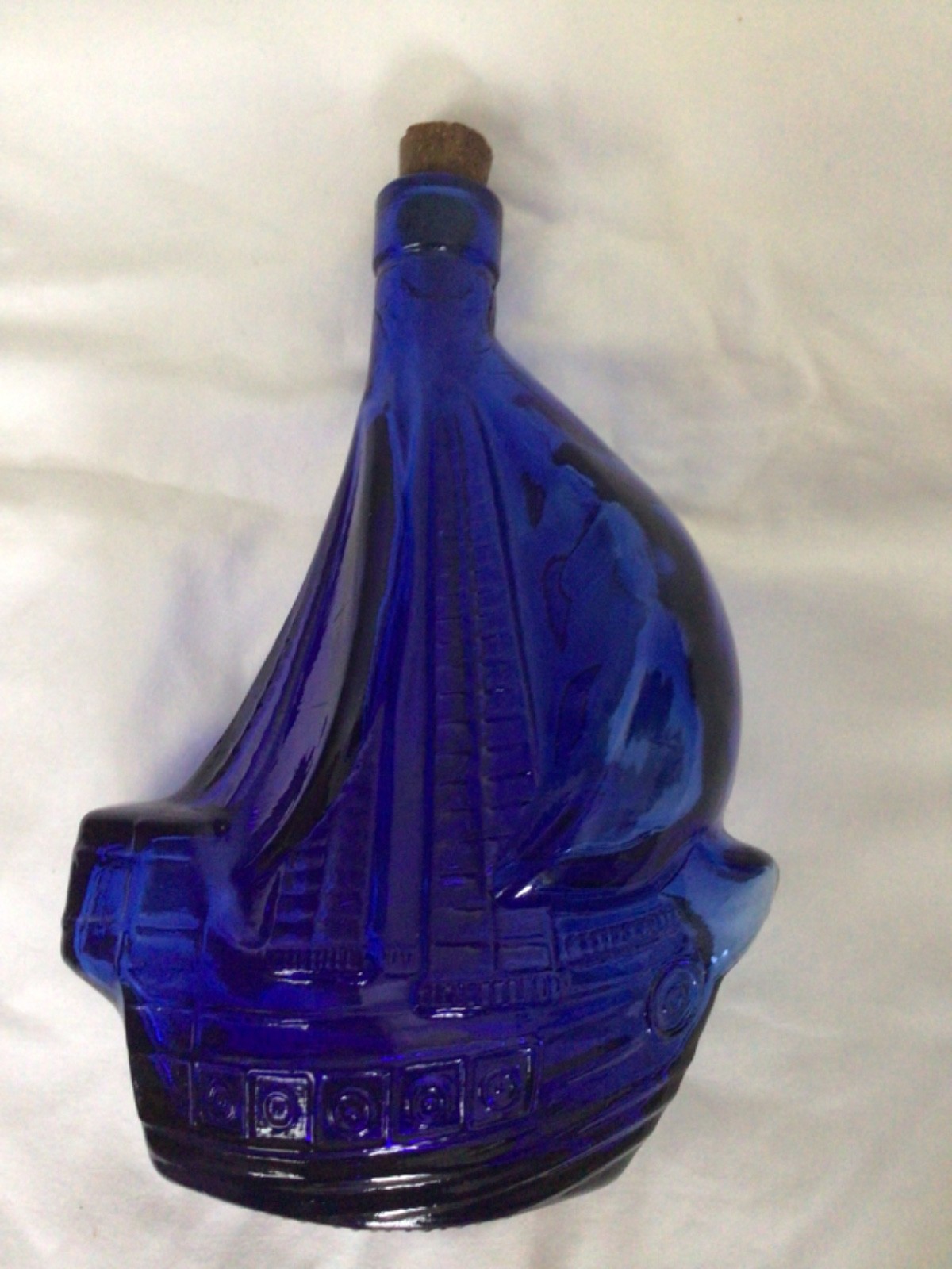Cobalt blue glass decanter shaped like a sailing ship, with a cork stopper.