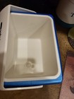 White rectangular Igloo cooler with blue top and sides, made in U.S.A., showing interior water level.