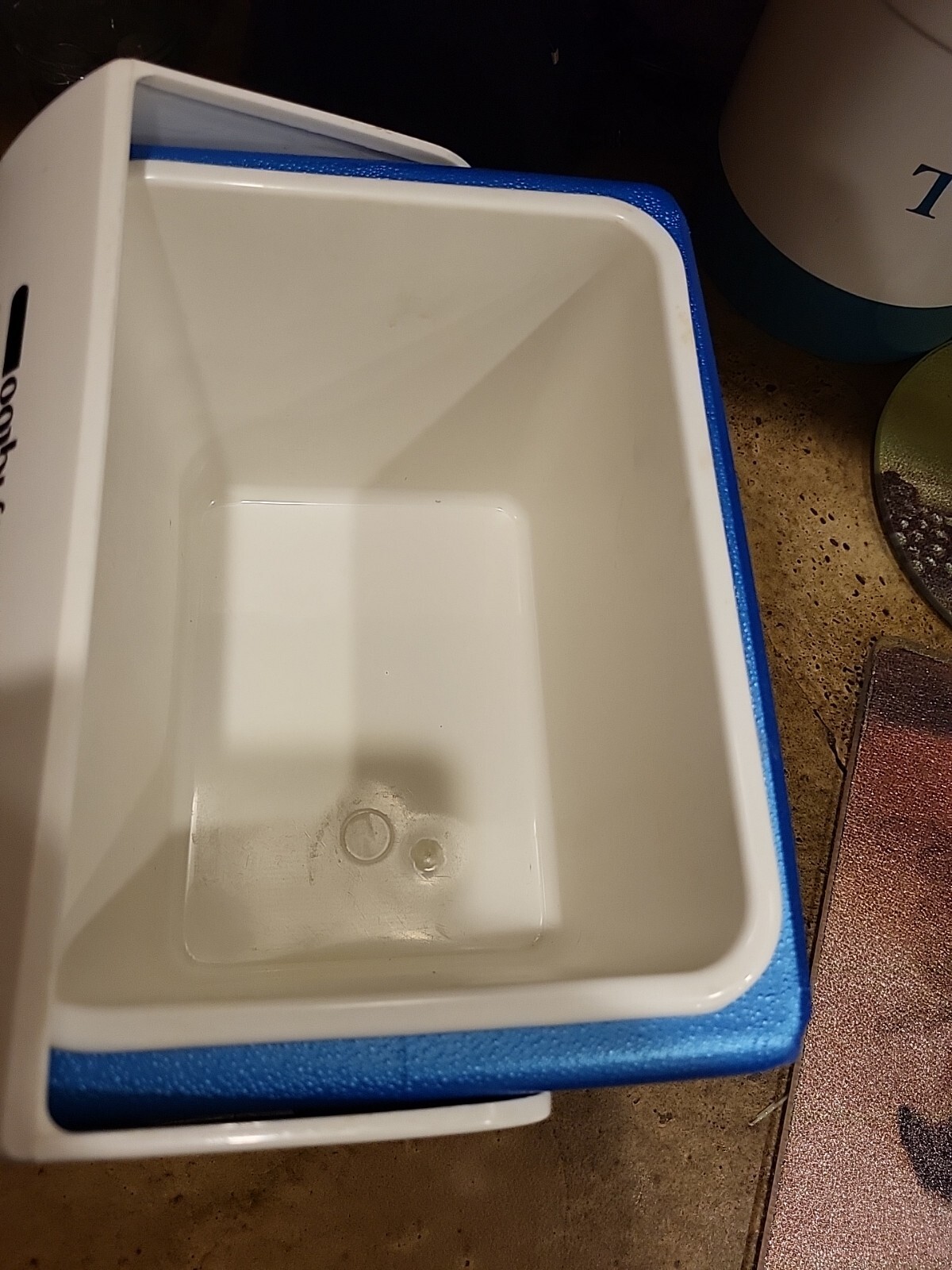 White rectangular Igloo cooler with blue top and sides, made in U.S.A., showing interior water level.