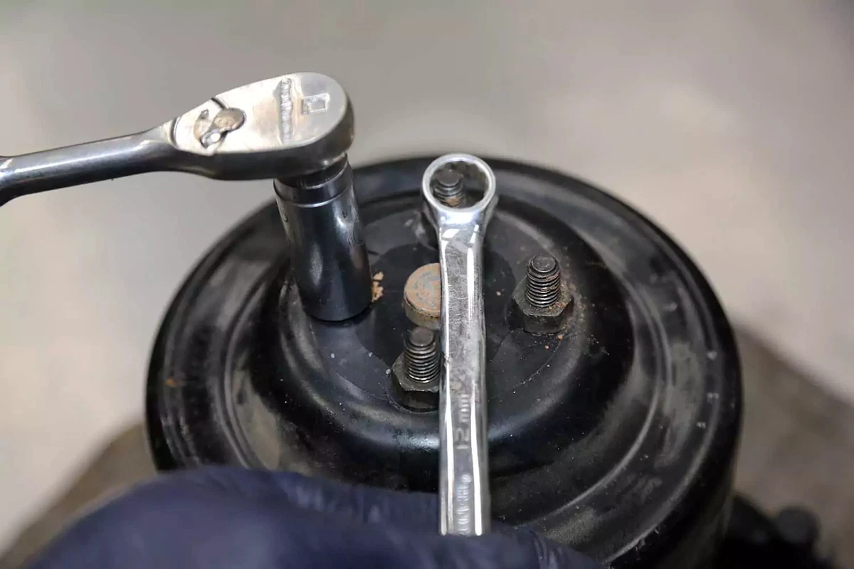Removing the water pump pulley with a box wrench and socket.