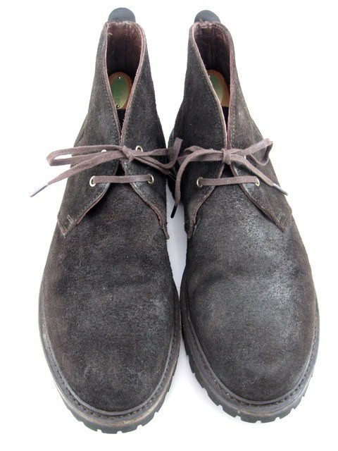 Pair of brown waxed suede chukka boots with a lug sole, tan laces, and a rounded toe.