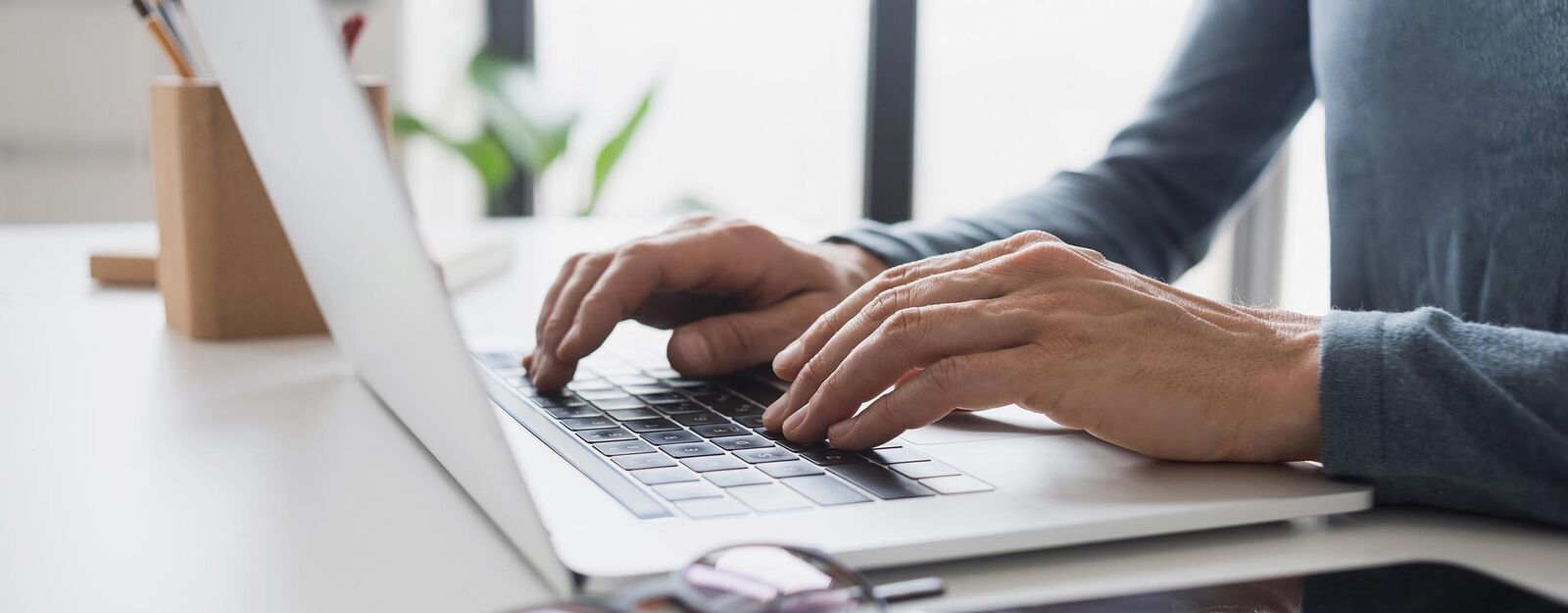 Ein Mann tippt auf einer Laptop-Tastatur