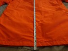 Orange cotton-nylon 70s-style parka with vertical seam detailing, shown against a measuring tape on a speckled gray surface.