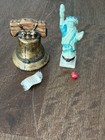 Miniature Liberty Bell with gold accents and matching Statue of Liberty figure, displayed on a wooden surface with red marble.