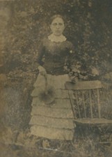 WOMAN IN RUFFLED SKIRT, HOLDING FAN. OUTDOOR SCENE.