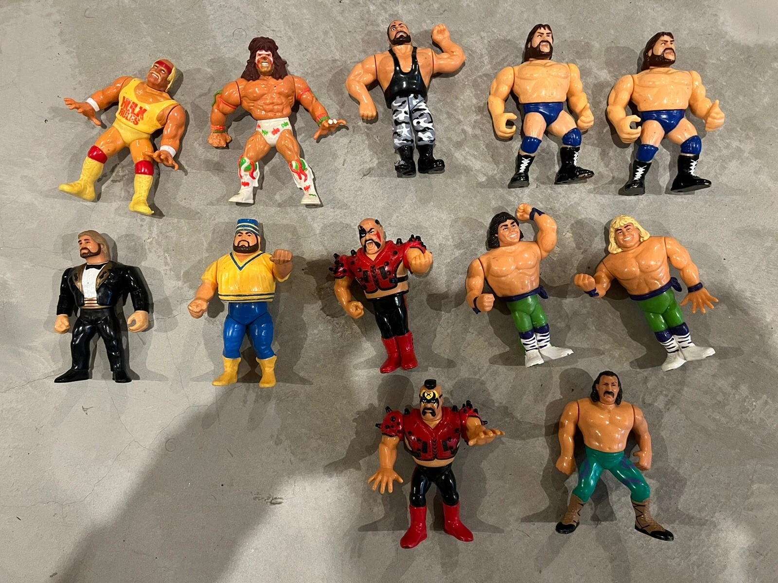12 WWF/WWE vintage action figures, 1980s/1990s, varied colors/patterns: wrestler in black tuxedo, wrestler in yellow outfit.