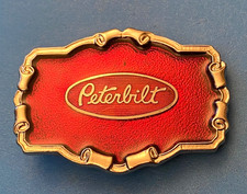 VINTAGE PETERBILT TRUCK BELT BUCKLE WITH HOOD ORNAMENT ON IT - CHROME ON RED