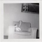 Infant with arm of hidden parent behind chair, 1960s — photo 1