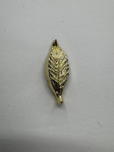 Goldfarbene Anstecknadel aus Kunststoff in Blattform