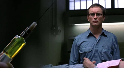Man in blue shirt holding syringe with green liquid and black needle, text “BEYOND RE-ANIMATOR” at bottom.