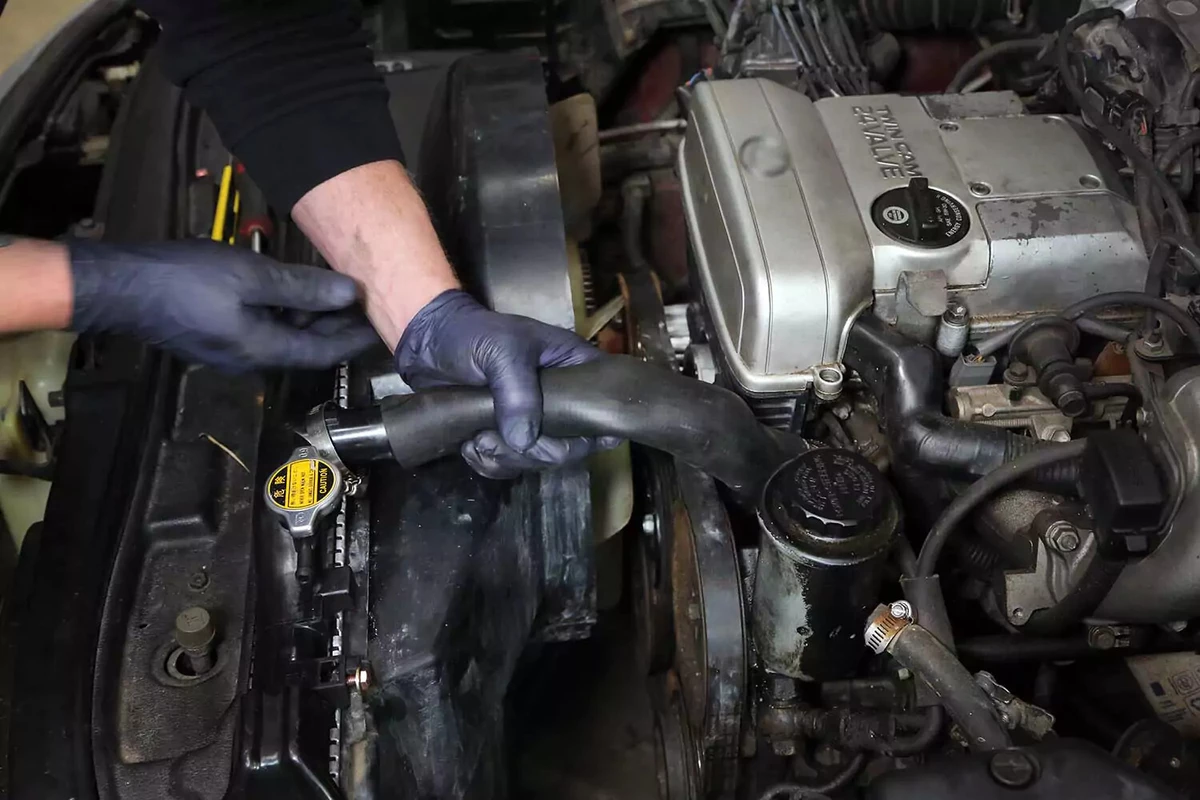 A mechanic handling a radiator hose.