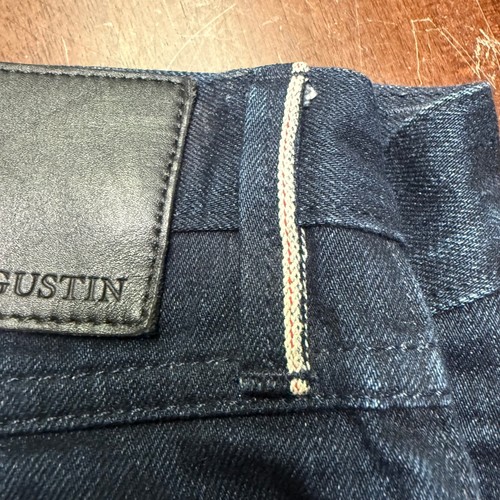 Black leather Gustin jeans patch on waistband, tan fabric strip, and white “GUSTIN” label on inner collar.