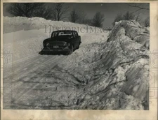 1959 Press Photo A car drives near 12-foot drifts on Swift Road near Pompey