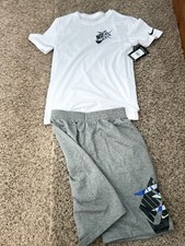Youth Nike Set With A White Nike Logo And A Grey Pair Of Shorts With The Logo