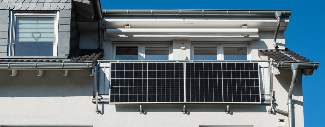 Nahaufnahme eines weißen Hauses mit einer kleinen Photovoltaikanlage auf der Frontseite.