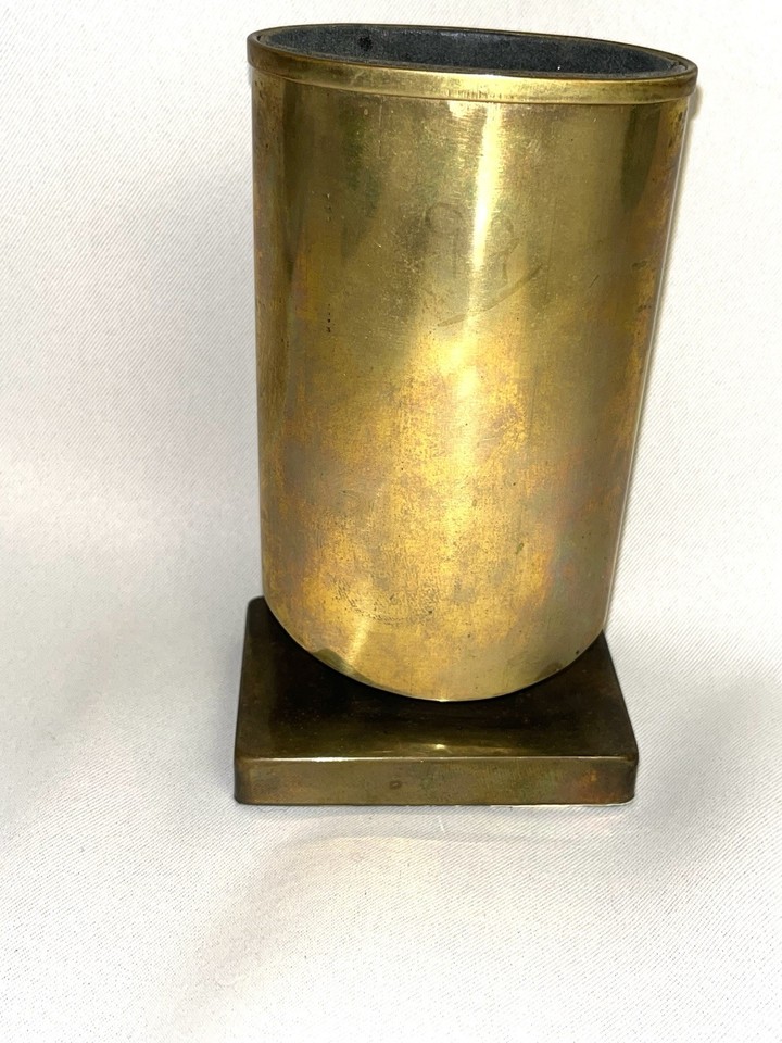 A footed brass eyeglass holder repurposed as a pen/pencil stand — the kind of elegant MCM desk piece you'd find in a Mad Men set.