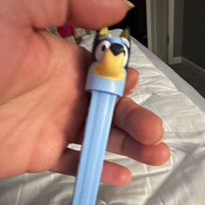 Distributeur de bonbons PEZ bleu avec tête de personnage dessin animé et tige bleu clair