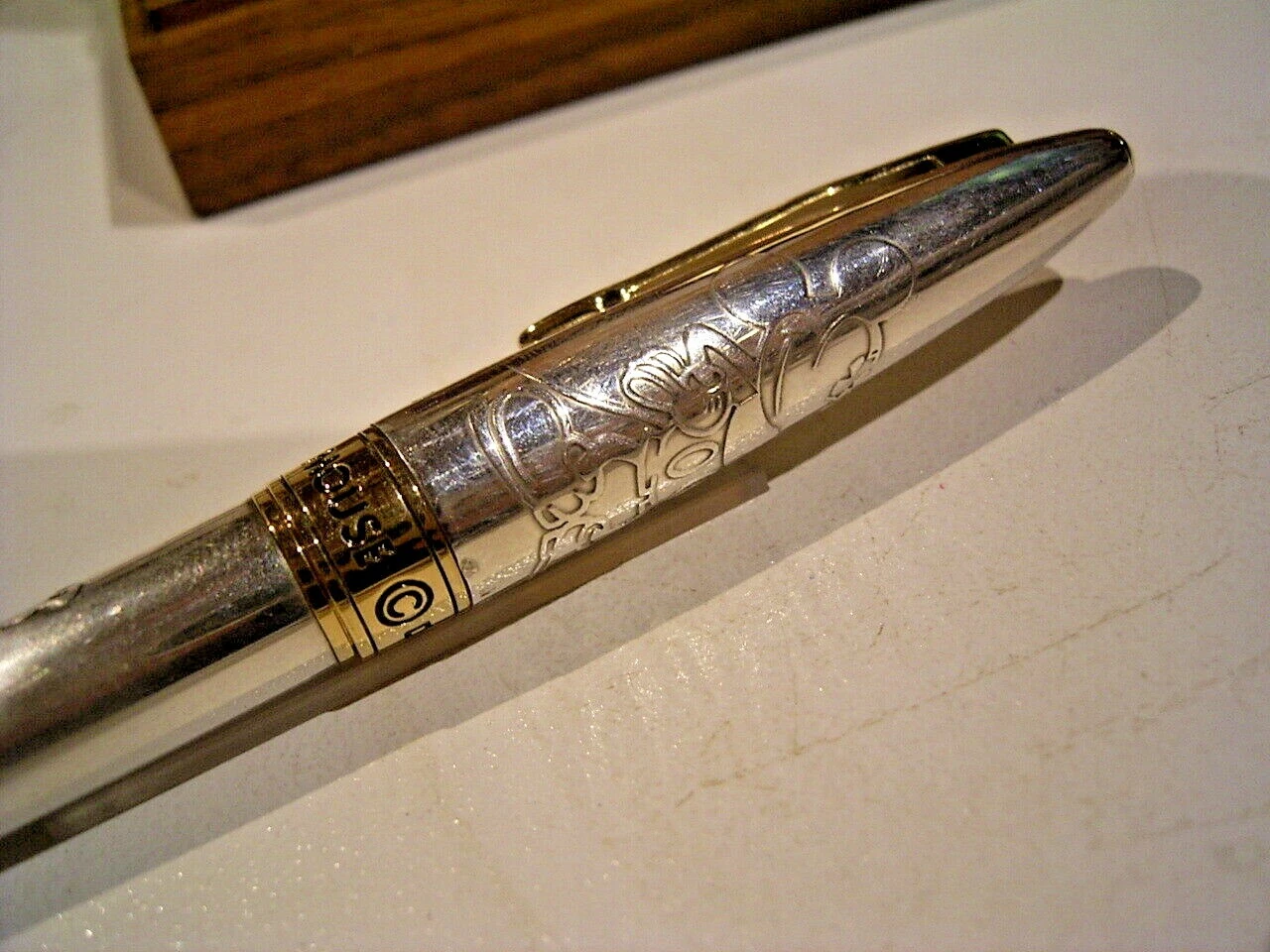Sterling silver Pilot pen with engraved Mickey Mouse design, gold band, and “PILOT” text on wooden box.