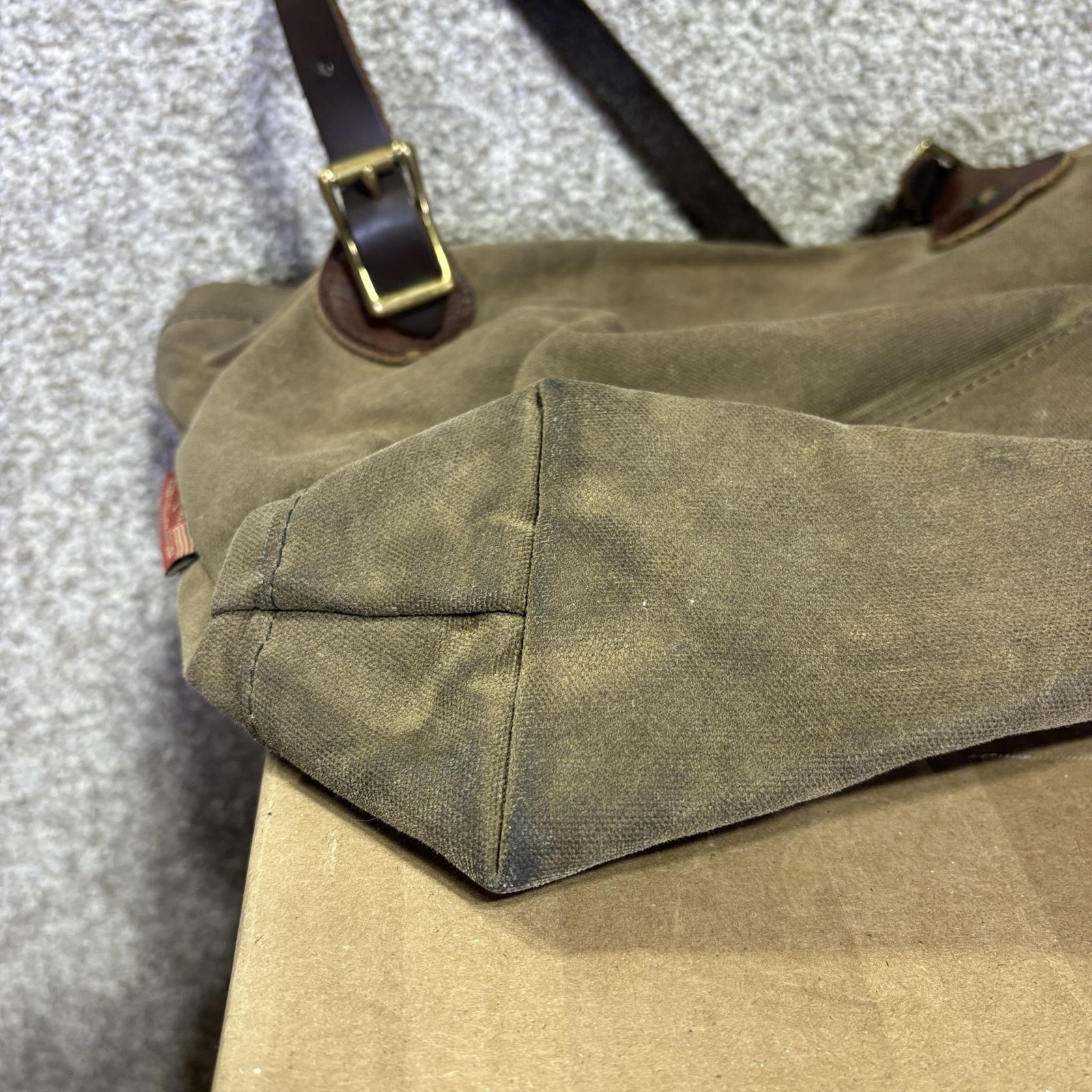 Brown canvas crossbody bag with leather trim, featuring a dark brown leather strap and brass buckle.