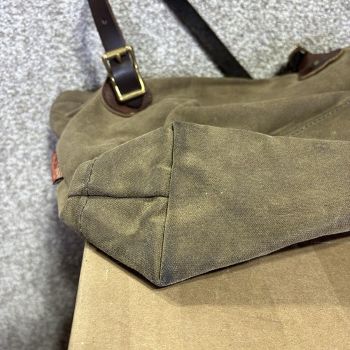 Brown canvas crossbody bag with leather trim, featuring a dark brown leather strap and brass buckle.