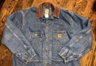 Blue denim Carhartt C59 DST chore coat with brown collar, front pocket, and small “Y2K” label on chest patch.