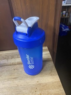 Bottiglia frullatore blu con coperchio dotata di beccuccio per un facile versamento.
