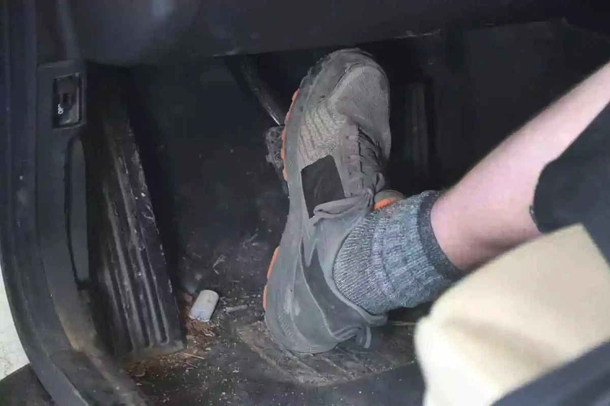 A mechanic presses a vehicle's brake pedal to test the brakes.
