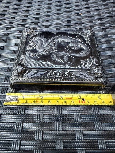 Silver metal Cruver Chicago Celluloid Dragon trinket box with ornate lid, shown on a dark textured surface.