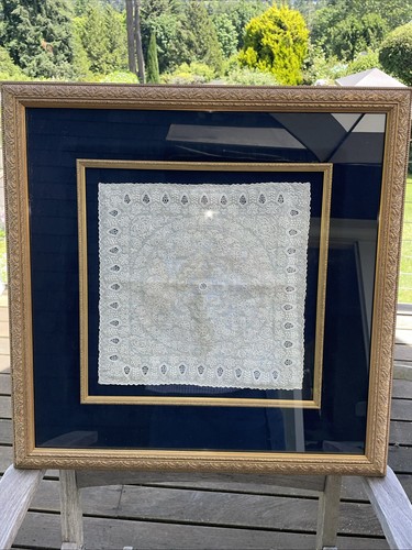 A framed antique handmade Irish linen handkerchief with intricate embroidery.