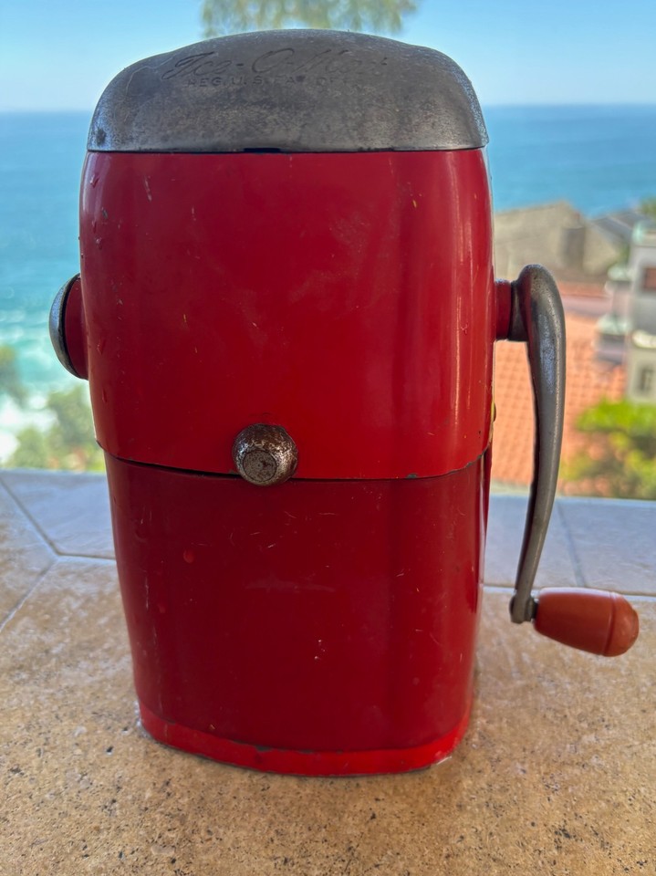 A fire-engine-red manual Ice-O-Mat hand-crank ice crusher — a retro barware showpiece that actually still works and looks incredible on a home bar cart.