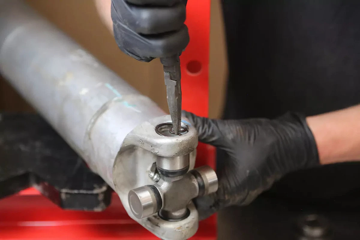 A mechanic wearing black gloves installs an inner clip to the cap.