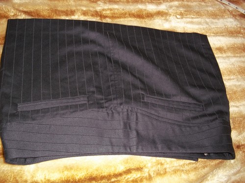 Black vintage pin stripe mini skirt with front welt pocket, belt loops, and double button closure, laid flat on fabric surface.
