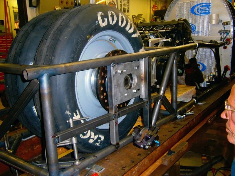True, working in his backyard workshop, tests the fit of the Truz Missile's tires.