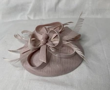 pink fascinator hat made of sinamay fabric with feather accents. 