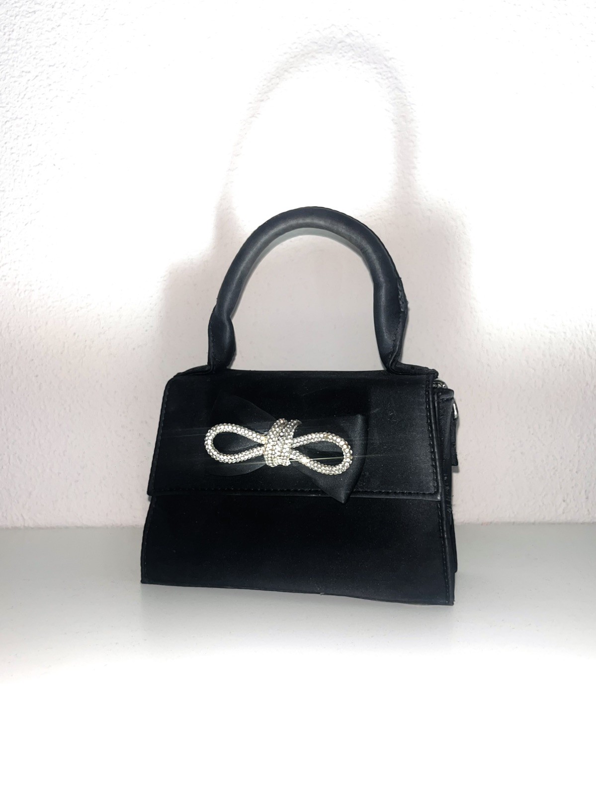 Bolso de mano negro con lazo de pedrería