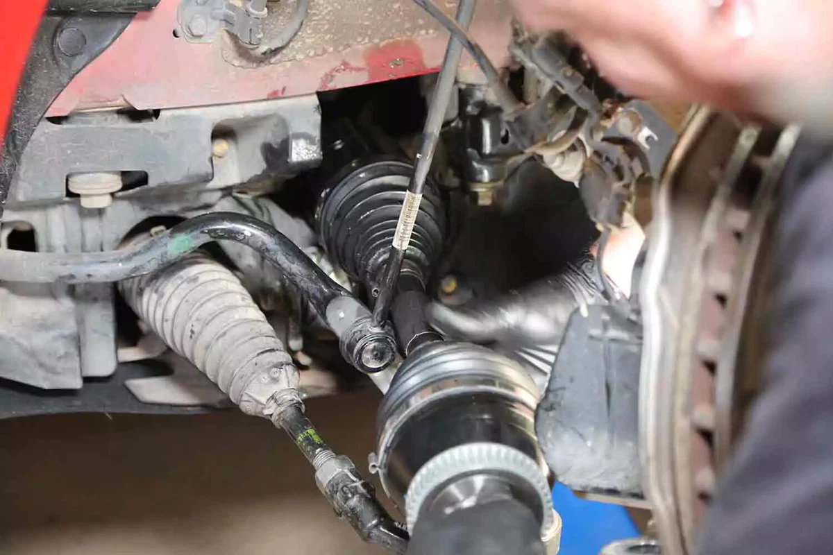 A mechanic wearing black nitrile gloves installs a new CV axle.