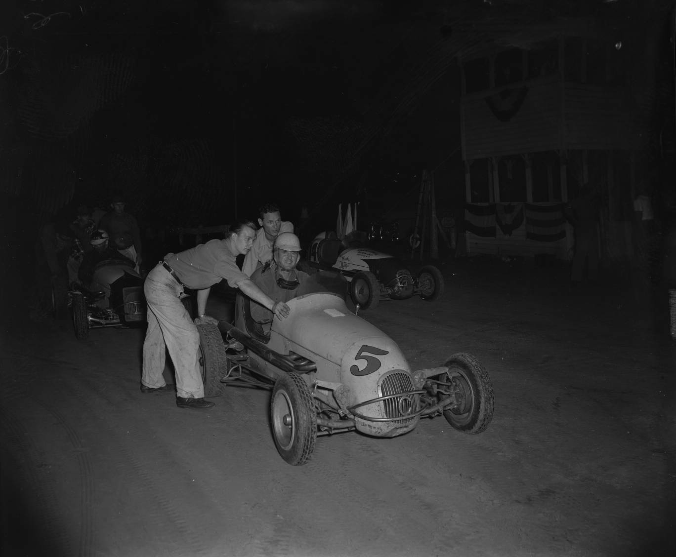 Midget Racer Duane Carter sits in car #5 as crew members push h 1949 ...