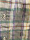 Men’s long-sleeve button-up shirt with green, purple, yellow, and red plaid pattern, featuring two chest pockets.