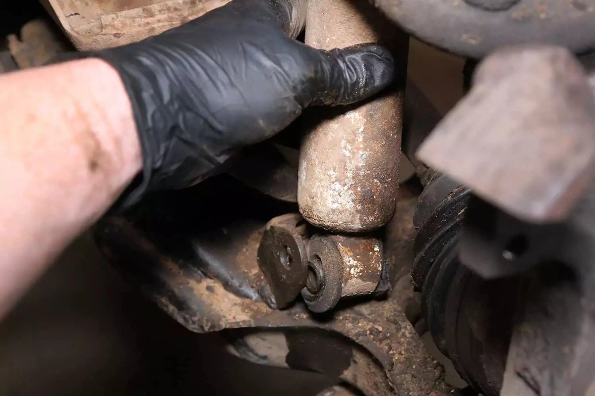 With the fasteners removed, a shock absorber is pulled from its mount.