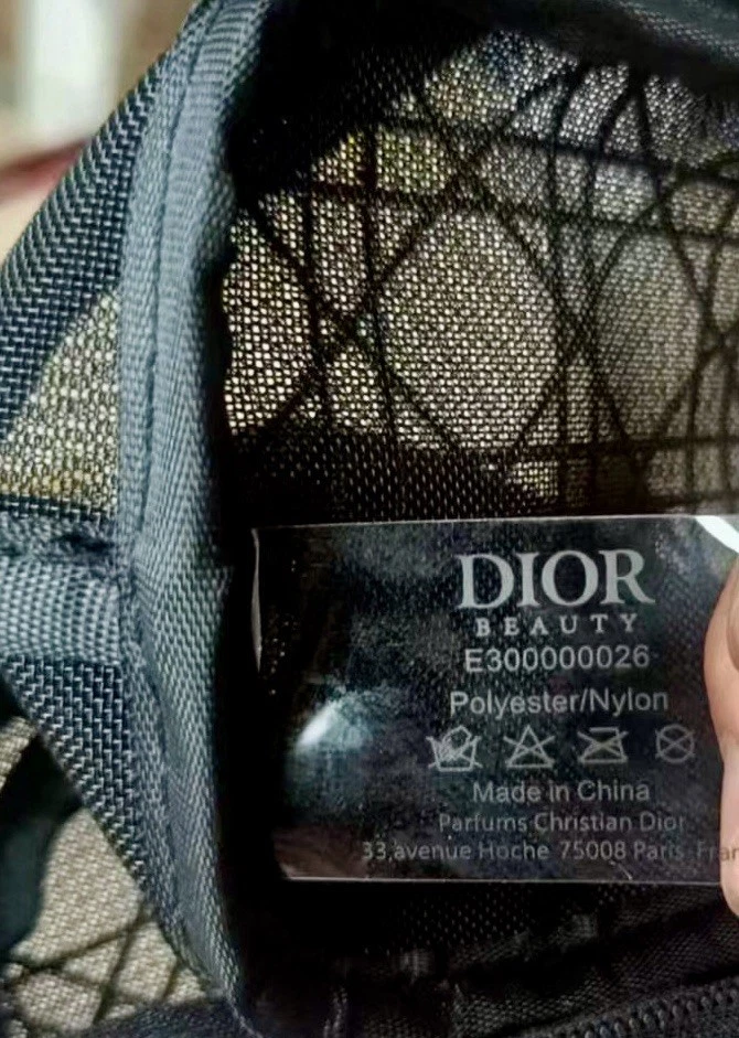 Black lace mesh tote with gold Cannage pattern, white tag on cream dust bag, labeled �DIOR BEAUTY� and washing icons.
