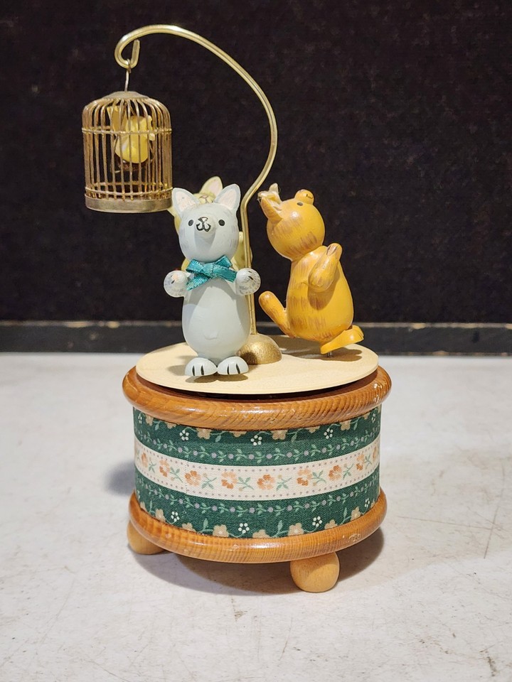 A 1988 animated musical sculpture of three cats staring at a bird in a cage — it moves, it plays music, and it's genuinely bizarre in the best possible way.