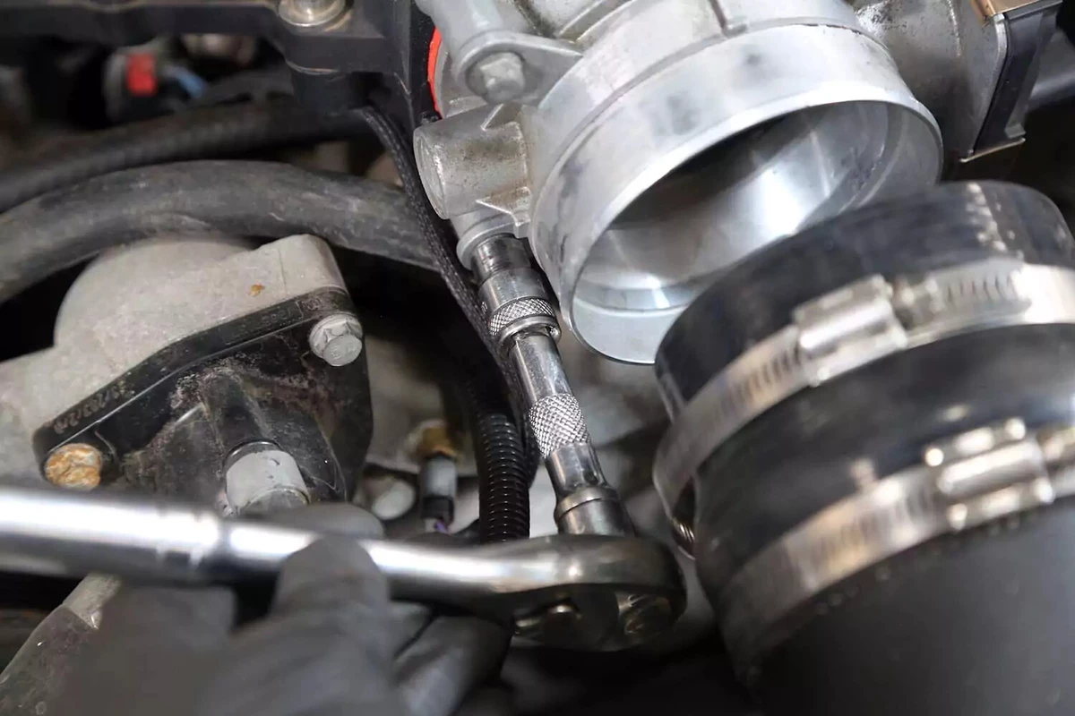 The bolts holding the throttle body to the intake are removed with a socket wrench.