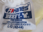 White fabric tag on red “Hanes” shirt, blue “Beefy-T” text, cotton, men’s, USA made, size L, color 42-44.
